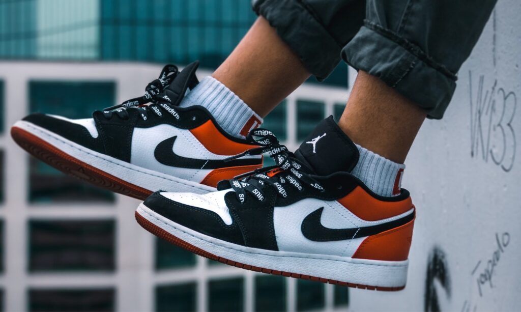 Nike Https Unsplash.comphotosman Sitting On The Ledge Of A Building Wearing Air Jordan 1 Low Top Shoes NoVnXXmDNi0